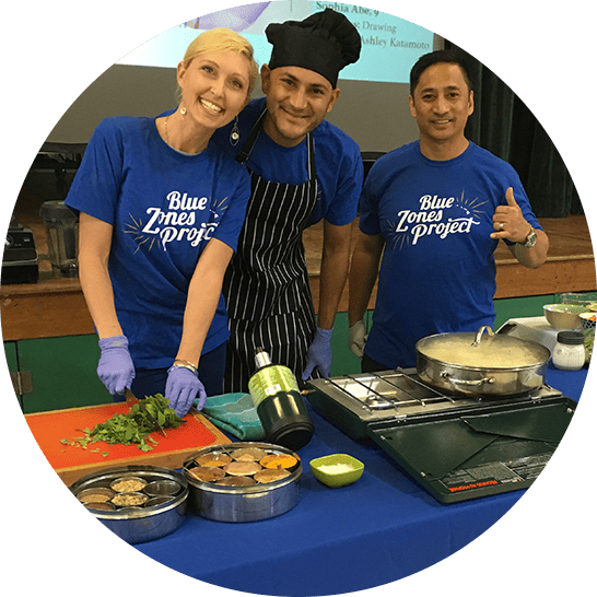 A chef and two volunteers demonstrating how to cook a meal